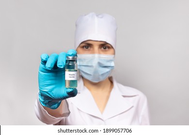 A Doctor Or Lab Technician Holds A Measles Vaccine. Measles Epidemic, Measles Encephalitis. The Concept Of Vaccination In Health Care.