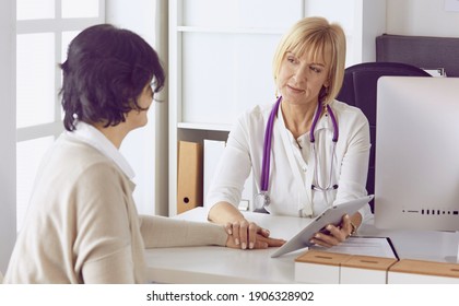 Arzt mit Laptop und schwangere Frau im Büro des Arztes