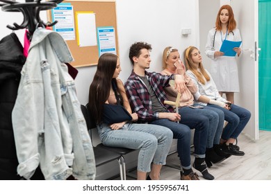 The doctor leaves the doctor's office and according to the list asks the next patient from the queue. People of different ages are sitting on chairs