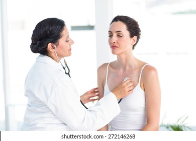 Doctor Listening To Patients Chest With Stethoscope In Medical Office