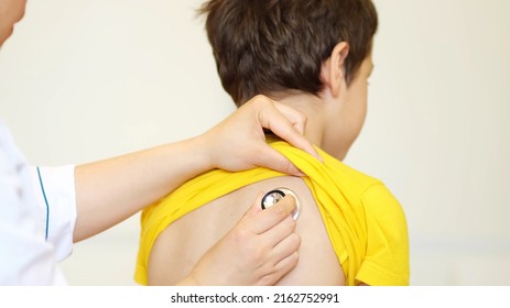 Doctor Listens To Breath Of Little Boy Through Stethoscope. Pediatrician With Stethoscope Listening To A Lungs In Child With Bronchitis And Cough