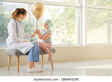 Doctor and little girl with golden balloon in clinic. Childhood cancer awareness concept - Shutterstock ID 1884493198