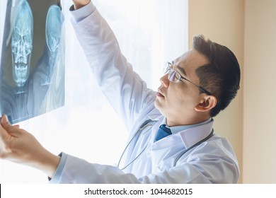 Doctor looking at film x-ray of patient head planning for surgery.