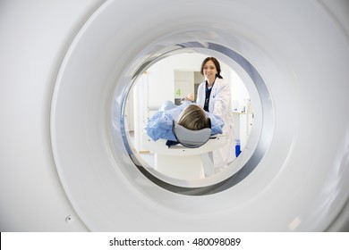 Doctor Looking At Patient Undergoing CT Scan