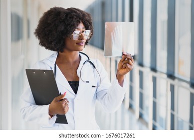 Doctor Looking Shoulder X-ray Film In Hospital. Radiography Concept. Radiology Female Doctor Examining X Ray Film Of Patient At Hospital Room.