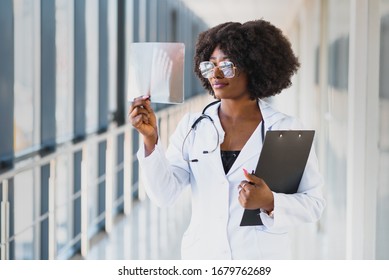 Doctor Looking Shoulder X-ray Film In Hospital. Radiography Concept. Radiology Female Doctor Examining X Ray Film Of Patient At Hospital Room.