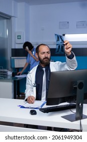 Doctor looking at x ray scan in hand for medical diagnosis, working late at night. Physician holding radiography exam results for analysis and examination. Medic with expertise - Shutterstock ID 2061949304
