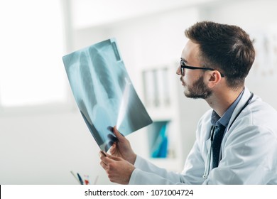 Doctor looking at x-ray in his office - Shutterstock ID 1071004724