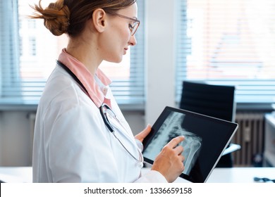 Doctor Looking At X-ray Picture Of A Shoulder On Her Modern Tablet Computer