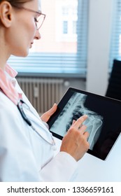 Doctor Looking At X-ray Picture Of A Shoulder On Her Modern Tablet Computer