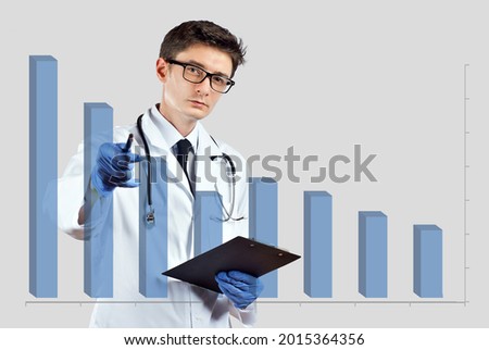 The doctor looks at the descending chart. The concept of reducing morbidity, vaccination and mortality. A man in a doctor's suit on a white background.