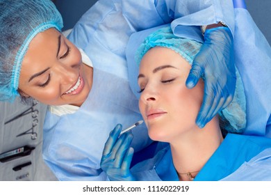 Doctor Makes A Cosmetic Injection In The Lower Lip Of A Mature Middle Age Patient Lying Down With Eyes Closed In A Surgery Room, O.R. Lip Filler, Beautify Concept.