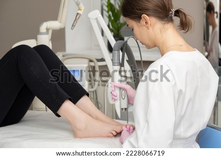 The doctor makes the procedure for the treatment of foot fungus. A patient receiving laser therapy for a toenail. Fungal infection on the nails. Treatment of onychomycosis with a medical laser Сток-фото © 