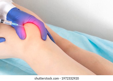 The doctor makes a puncture with intra-articular injection of drugs into the patient's knee joint. Injection of medication into a sore knee, therapy - Shutterstock ID 1972332920