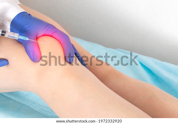 The doctor makes a puncture with\
intra-articular injection of drugs into the patient\'s knee joint.\
Injection of medication into a sore knee,\
therapy