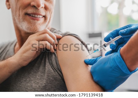 Doctor making injection to senior patient in clinic
