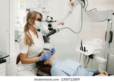 Doctor making teeth examination research survey using microscope in dentistry. Dentist is treating patient in modern dental office. - Powered by Shutterstock