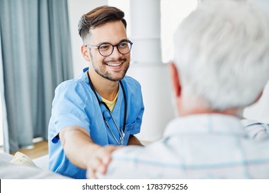 Doctor Or Male Caregiver With Senior Man Holding A Cane On Sofa At Home Or Nursing Home