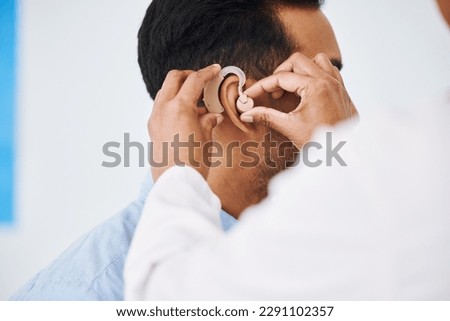 Doctor, man and hearing aid on ear for medical support, wellness and innovation of disability. Closeup, healthcare worker and deaf patient with audiology implant, service and help for sound waves