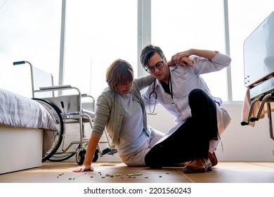 Doctor Man Help To Support Senior Woman Who Fall From Wheelchair To Floor Of Patient Room And Medicine Are Spread On The Floor.