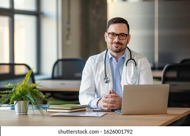 Doctor man sitting at the desk at his working place and smiling at camera. Perfect medical service in clinic. Portrait of a handsome young doctor. Happy doctor looking at camera  - Powered by Shutterstock