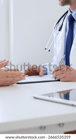Doctor man taking notes while listening to a female patient explaining her symptoms during a medical consultation in the clinic office. Medicine and health care concept