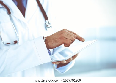 Doctor man using tablet computer for network research or virtual disease treatment, hands close-up. Perfect medical service in clinic. Modern medicine, medic data and healthcare concepts. Toned