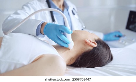 Doctor man wearing blue medical gloves is using ultrasound equipment on neck of female patient lying down for a medical examination - Powered by Shutterstock