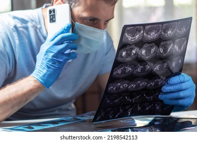 Doctor In Mask Attentively Examines Head MRI And Calling Pacient.