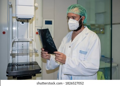 Doctor With Mask Checking Mammography Of Woman In X-ray Room.