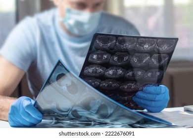 Doctor In Mask Examines And Compares Two MRI Scans.