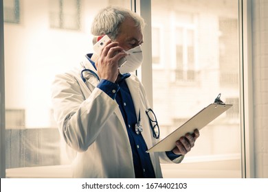 doctor with mask using mobile phone and reading clinical reports