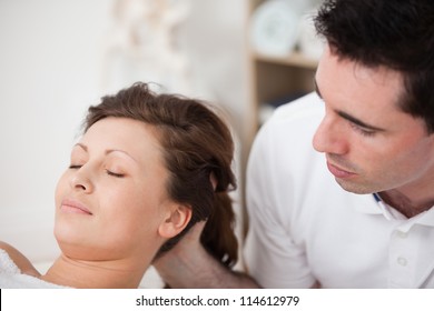 A doctor massaging the head of his patient while holding it in a room