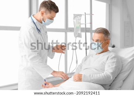Doctor and mature man undergoing course of chemotherapy in clinic