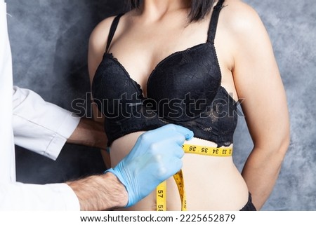 doctor measures the waist of a woman in bras