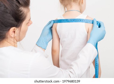 The Doctor Measures The Width Of The Child's Shoulders, Development And Growth With A Measuring Tape. Measurement Of Anthropometric Data. 