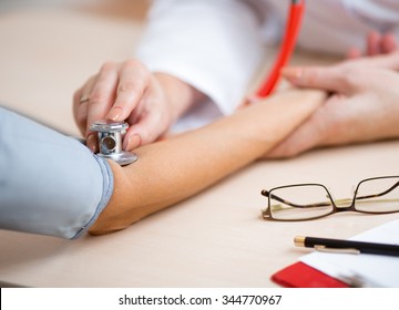 Doctor measuring blood pressure at desk