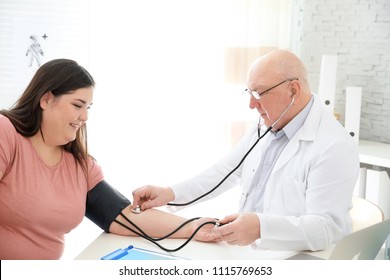 Doctor measuring blood pressure of overweight woman in clinic
