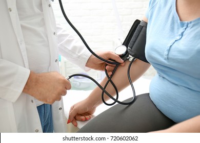 Doctor Measuring Blood Pressure Of Overweight Woman In Hospital