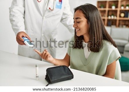Doctor measuring glucose to latin woman at clinic