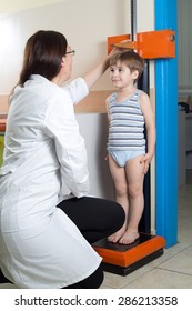 Doctor Measuring Height Of Little Boy On Traditional Medical Scale