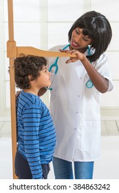 Doctor Measuring Height Of Little Boy On Traditional Medical Scale