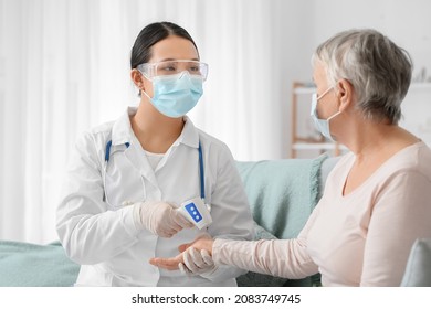 Doctor measuring temperature of senior woman at home - Shutterstock ID 2083749745