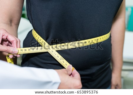 Doctor measuring waist of patients, checking for Body mass index (BMI).