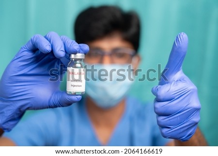 Doctor with medical face showing malaria vaccine bottle with thumbs-up gesture - concept of new successful Malaria vaccination