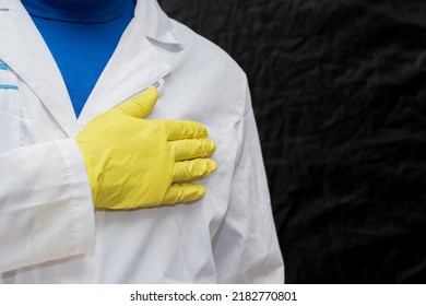 A Doctor In A Medical Gown And Protective Gloves Holds His Hand Over His Heart. The Face Is Not Visible. Put Your Hand On Your Chest During A Hymn Or Oath.