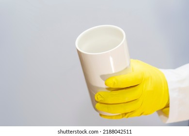 A Doctor In A Medical Gown And Protective Gloves Holds In His Hand A Large White Container Without Inscriptions. The Face Is Not Visible. Empty Template For Text.