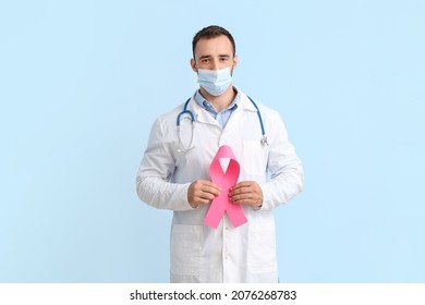 Doctor In Medical Mask And With Pink Ribbon On Color Background. Breast Cancer Awareness Concept