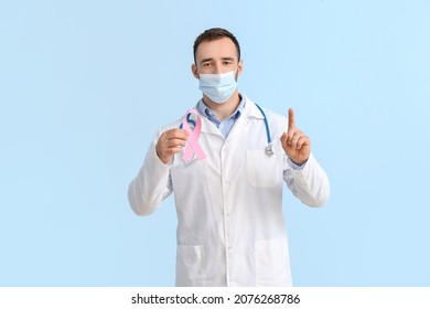 Doctor In Medical Mask And With Pink Ribbon On Color Background. Breast Cancer Awareness Concept