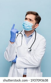 doctor in medical mask and white coat with stethoscope having idea isolated on blue